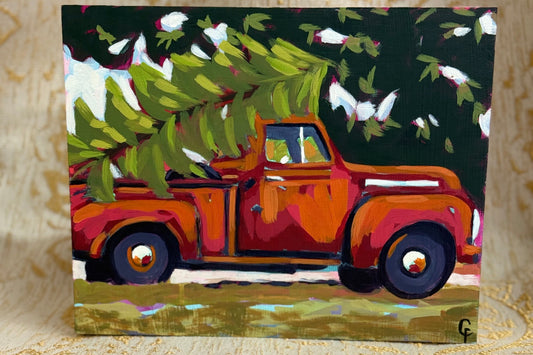 Painting of an orange truck with a Christmas tree on a decorative surface